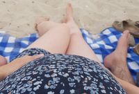 Schwangere Person sitzt am Strand